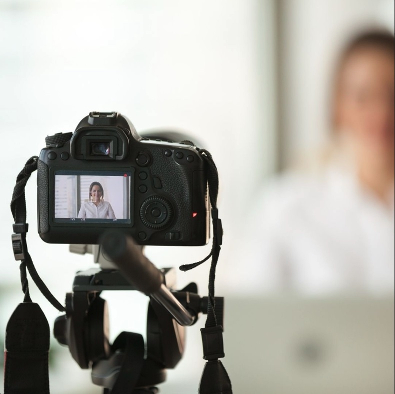 Appareil photo pro en train de filmer une jeune femme